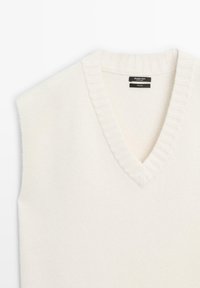 Gilet sans manches en laine couleur crème avec col en V et bordures côtelées, étiqueté Massimo Dutti, fabriqué en Chine.