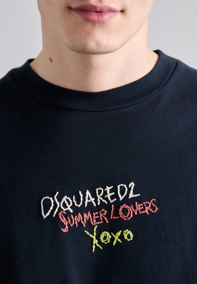 Tumesinine puuvillane sviiter ümarate kaelustega, millel on multivärviline tikitud tekst "DSQUARED2 SUMMER LOVERS Xoxo" erinevates fontides.