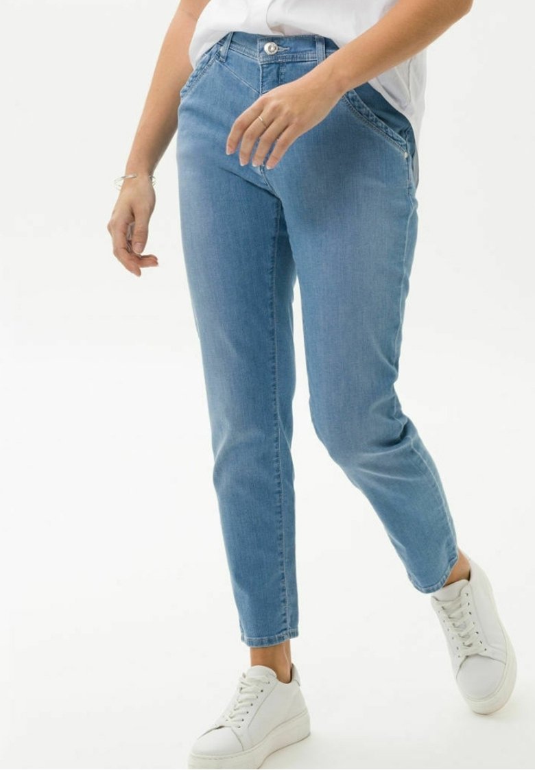 Ljusblå denimjeans med slim fit, med en klassisk femficksdesign och knappstängning. Bärs med vita sneakers.