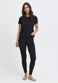 Juoda trumpomis rankovėmis marškinėliai derinami su juodomis tamprėmis, abu pagaminti iš lygaus medvilninio audinio, turintys laisvą fasoną be raštų.