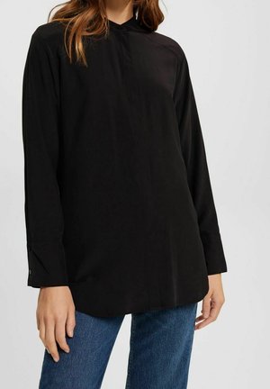 Black long-sleeve shirt with a buttoned collar, smooth texture, and a loose fit, paired with blue denim jeans.