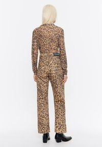 Lepardo-print blouse met lange mouwen en wijde broek in bruin tinten, met een aansluitende taille en een zachte, gladde stof. Zwarte enkellaarsjes.