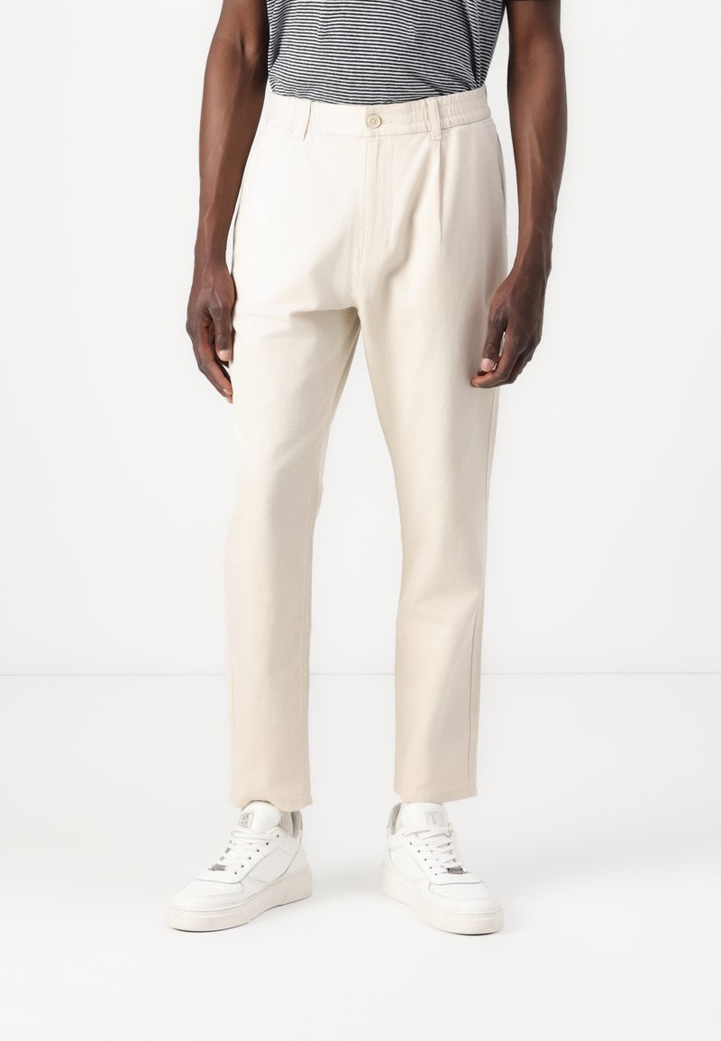 Beige broek met een tapered fit, gemaakt van lichtgewicht stof. Voorzien van een knoopsluiting, zijzakken en subtiele stikdetails.