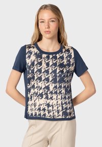 Camiseta de manga corta azul marino con un patrón abstracto en crema y azul marino, cuello redondo y un tejido suave. Diseño de ajuste relajado.