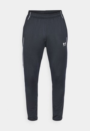Fekete sportnadrág sima anyagból, rugalmas derékrésszel, tapered lábakkal és fehér oldalsávokkal. Az Under Armour logója is megtalálható rajta.