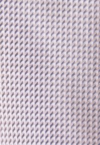 Gros plan sur un tissu tissé présentant un motif diagonal de fils clairs et foncés dans un dessin en chevrons répété.