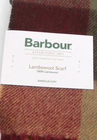 Lamswol sjaal in een mix van rode, bruine en groene tinten, met een zachte, gestructureerde oppervlakte en een label met "100% Lamswol" van Barbour.