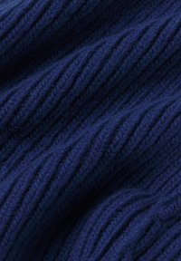 Tejido de punto azul oscuro con textura de canalé vertical. El material parece suave y denso, resaltando la intrincada costura y la rica profundidad del color.