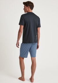 Dark gray short-sleeve T-shirt paired with blue patterned shorts. The shorts feature a geometric print and relaxed fit, suitable for casual wear.