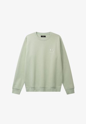 Lys grønn genser laget av mykt materiale, med rund hals, lange ermer og et lite hvitt smilefjes på brystet.