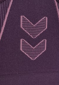 Lila Textil mit zwei nach unten zeigenden Chevron-Mustern in einem helleren Rosa-Ton, mit einer strukturierten Oberfläche und geripptem Detail am unteren Rand.