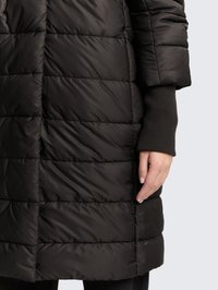 Fekete, téglalap alakú steppeléssel készült bélelt kabát, magas gallérral és bordázott mandzsettákkal. Sima textúrájú, fényes felülettel és oldalzseb részlettel.