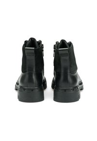 Czarne botki na kostkę wykonane ze skóry i zamszu, z teksturowaną cholewką, zapinane na zamek oraz posiadające masywną gumową podeszwę z wyraźnym wzorem bieżnika.