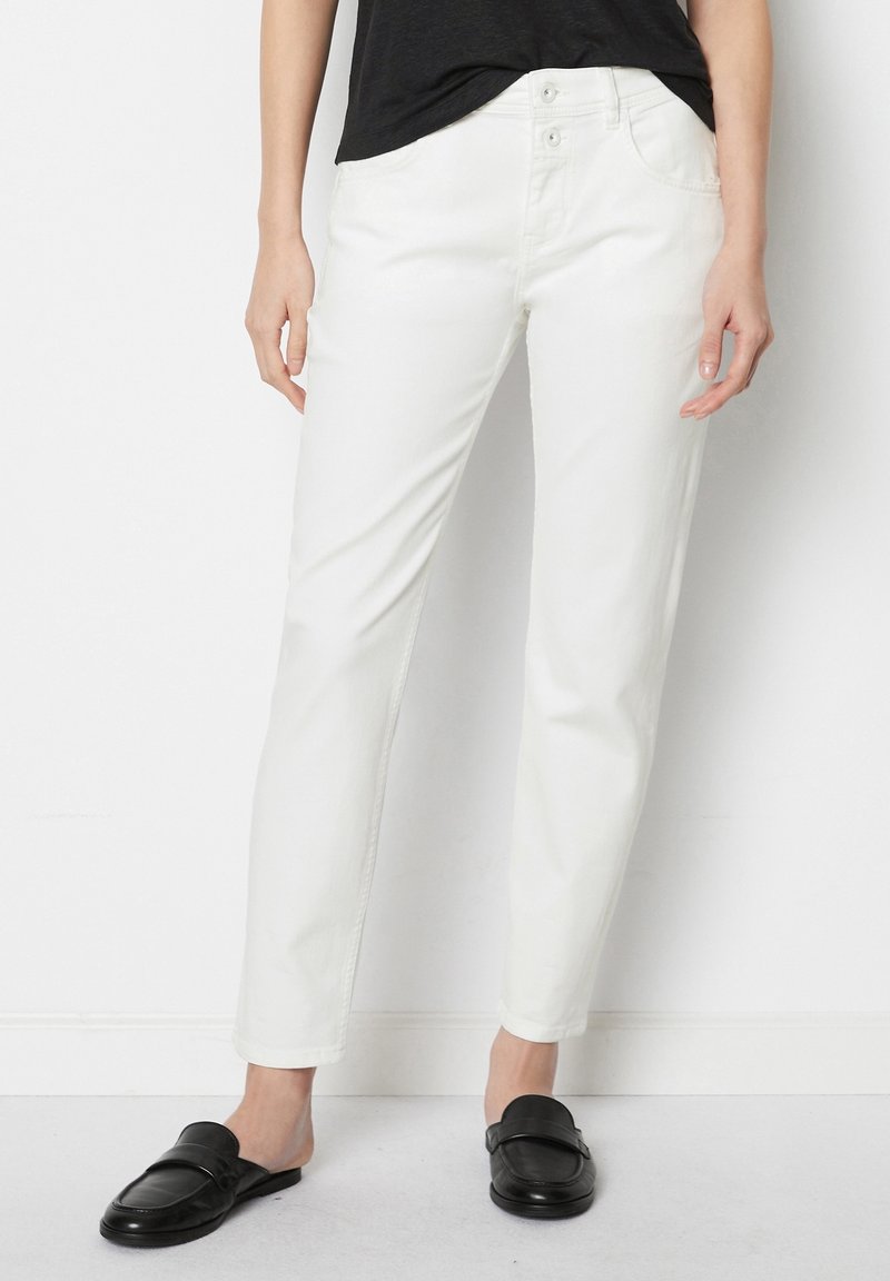 Vita, raka jeans i lättviktig bomull. Har en knappdesign i grenen, framfickor och en slät, jämn yta. Stylade med svarta loafers.