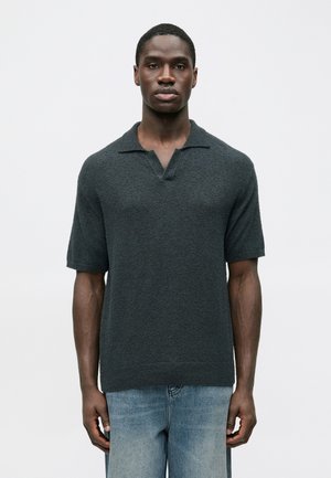 Polo en maille à manches courtes gris foncé avec une finition texturée et un col en V. Associé à un jean denim bleu clair.