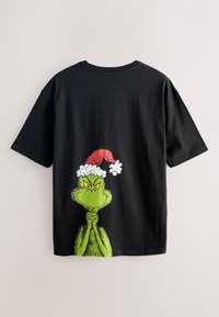 Melna kokvilnas T-krekls ar zaļu Grinča attēlu un sarkanas un baltas Ziemassvētku cepures motīvu uz muguras. Īsas piedurknes un brīvs piegriezums.