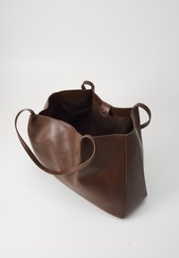 Borsa tote in pelle marrone con un ampio interno, manici piatti e chiusura a bottone, caratterizzata da una texture liscia e un design minimalista.