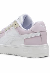 Sneaker Puma con parte superiore in pelle bianca, dettagli in lavanda e suola in gomma texturizzata. Presenta un collare imbottito e allacciatura frontale.