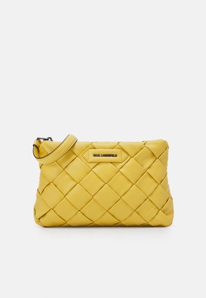 Żółta pikowana kopertówka ze skóry z paskiem na nadgarstek i metalową plakietką z logo marki umieszczoną na środku przedniej strony.