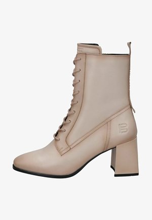 Botas de tobillo de cuero beige con punta afilada, que cuentan con un cierre de cordones en la parte frontal, un tacón cuadrado y un logo en relieve en el lado exterior.
