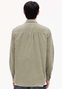 Langærmet shirt in effen lichtolijfgroen, met een soepele textuur, knoopmanchetten en een rugplooi.