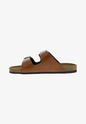 Sandale en cuir marron avec deux sangles réglables, semelle en liège et semelle plate. Présente une texture lisse et un design minimaliste.