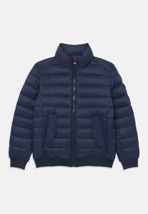 Giacca puffer blu navy con collo alto, zip frontale, due tasche con bottone e polsini a coste. Caratterizzata da una texture imbottita e una struttura leggera.