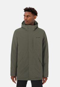 Veste imperméable vert olive avec un col haut, capuche ajustable et poches frontales doubles. Présente une texture mate élégante et un branding minimal.