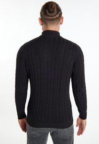 Maglione nero a maglia rasata con colletto alto, caratterizzato da polsini e orlo a coste, realizzato in un tessuto a maglia texturizzato, design aderente.