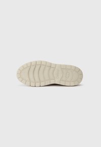Sole di sneaker beige con un motivo di grip testurizzato caratterizzato da varie forme e contorni. La base è piatta con un design a punta arrotondata.
