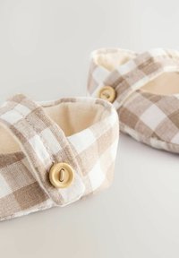 Syntetiske slippers i en beige og hvid ternet struktur. Med en strop der har en træknap som accent. Blød og afrundet design.