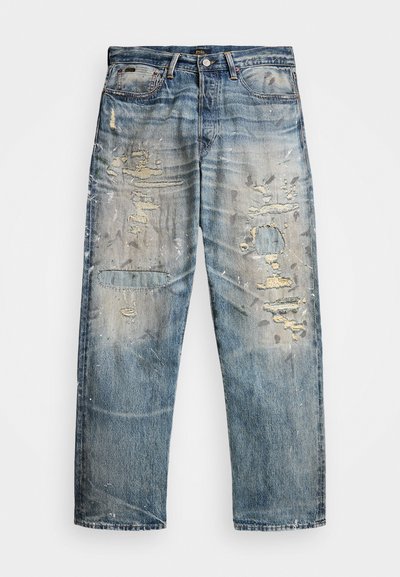 Svetlo modri denim kavbojke s sproščenim krojem, ki vključujejo obrabljena mesta, strgane robove in subtilne barvne madeže, kar poudarja staran videz.