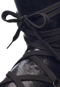 Must must elastne kummik, millel on tekstuuriga viimistlus, mustad paelad, mis on kindlalt seotud kaaresse. Lisadeks on väike metallnööpdetail.