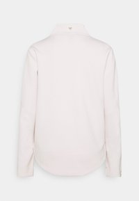 Chemise blanche à manches longues avec col, ourlet arrondi, poignets boutonnés et petit détail en forme de cœur sur le col arrière.