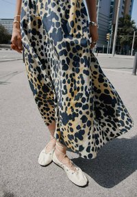 Midi šaty s leopardím vzorem v béžové a námořnické barvě, vyrobené z lehkého materiálu a s volným střihem; doplněné krémovými baletními botami s křížovými popruhy.