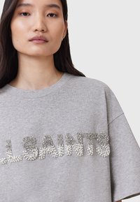 Grå oversized t-shirt med prydet "ALLSAINTS" skrift, korte ærmer, rund hals og blød bomuldsstruktur.