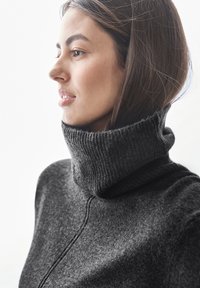 Mörkgrå höghalssweater med texturerad ribbstickad krage och mjukt tyg, med en slät kropp och sömlös design.