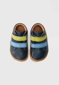 Pantofi din piele albastri și verzi cu două curele Velcro, interior maro și talpă din cauciuc natural, având o textură netedă și un design cu vârf rotund.