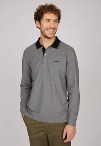 Polo à manches longues en tissu texturé gris avec un col noir, un bouton blanc et des surpiqûres contrastées. Logo sur la poitrine gauche.