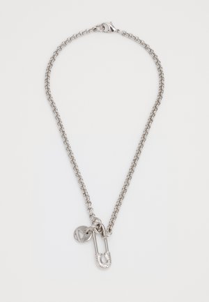 Silver chain necklace featuring a large safety pin charm and a small round pendant with a logo detail. Smooth, metallic finish.