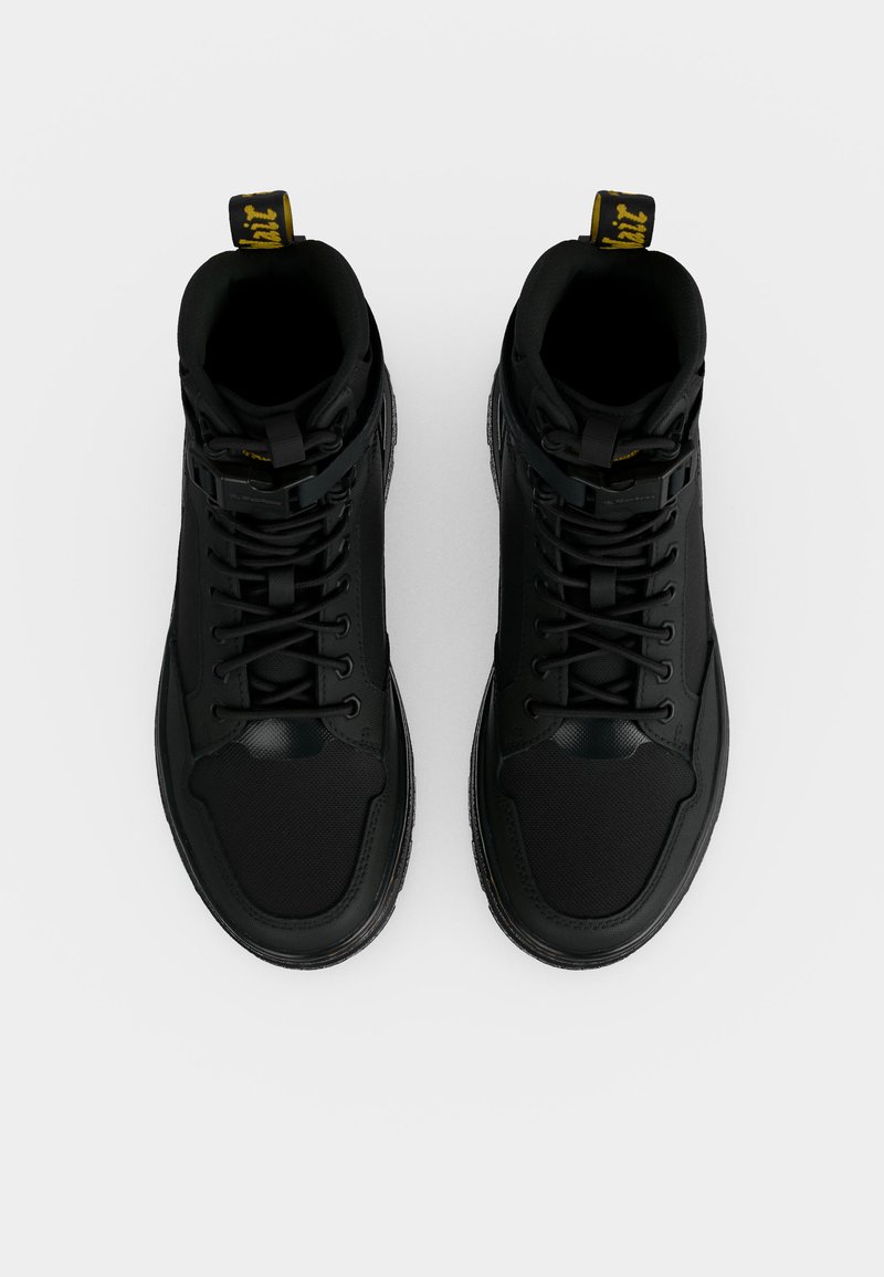 Pair of black high-top sneakers with laces and yellow text on pull tabs, shown from top view on a white background.
