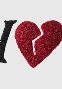 Zwarte getextureerde letter "I" naast een rood getextureerd gebroken hartvorm op een effen lichte achtergrond.