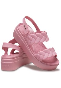 Sandales à plateforme roses en matériau flexible, avec un design de bride tressée et une sangle arrière ajustable comportant plusieurs trous.