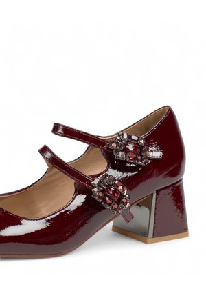 Zapatos de charol burdeos con punta cuadrada, dos correas en el tobillo y acentos decorativos. Tacón cuadrado con un detalle metálico.