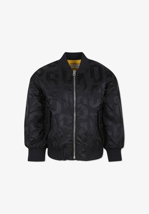 Veste bomber noire avec une texture brillante et matelassée, un imprimé logo subtil, des poignets côtelés, une fermeture éclair à l'avant et une doublure intérieure jaune.