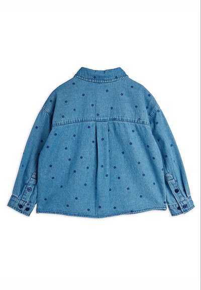 Πίσω όψη μιας μπλε denim πουκάμισας με μακριά μανίκια, σκούρα μπλε πουά και μανσέτες με κουμπιά σε λευκό φόντο.