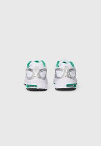 White athletic shoes with silver accents, green details, and a textured mesh upper. Features a padded ankle and a black rubber sole.