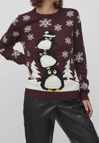 Burgundy stickad tröja med tre staplade pingviner i vitt och gult, med vita snöflingor och träd som mönster.