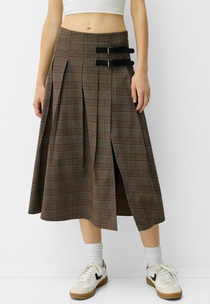 Falda midi de cuadros marrones con pliegues, doble hebilla negra en la cintura y una abertura lateral, confeccionada en un tejido texturizado.
