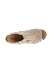 Chaussure slip-on en tricot beige avec un bout arrondi, fermeture éclair et accents cloutés sur la zone des orteils. Texture douce et design minimaliste.